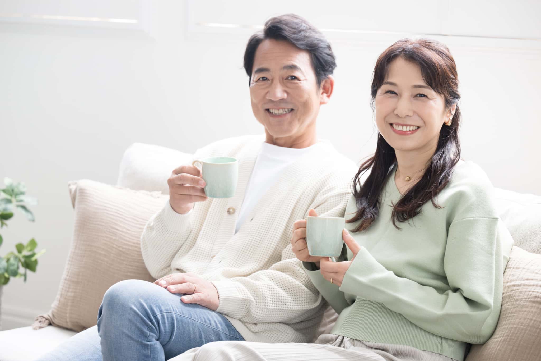 ソファで飲み物を楽しんでいる歯周外科治療で健康な口腔環境になった夫婦