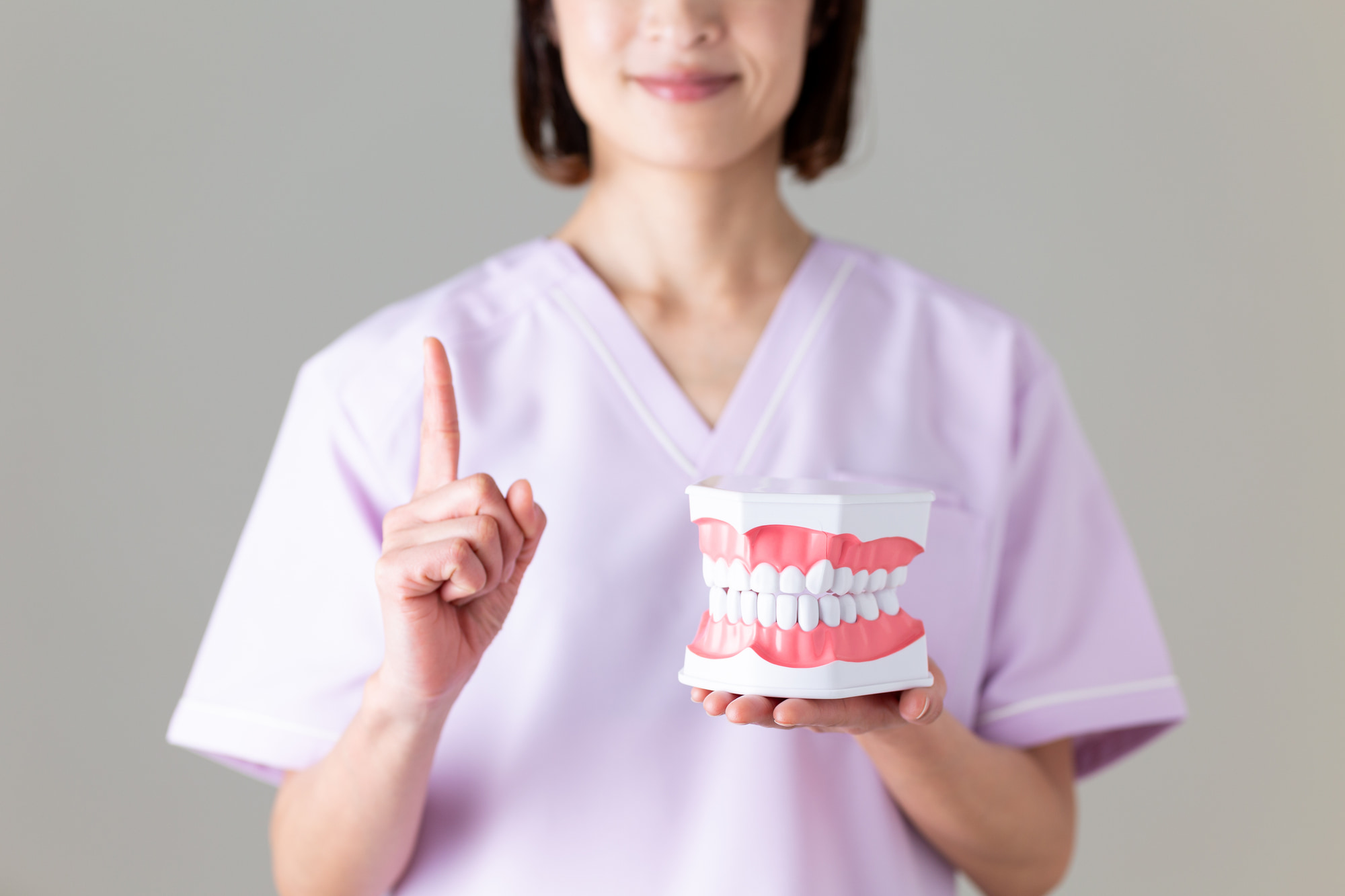 歯周外科治療について歯の模型で説明する歯科医