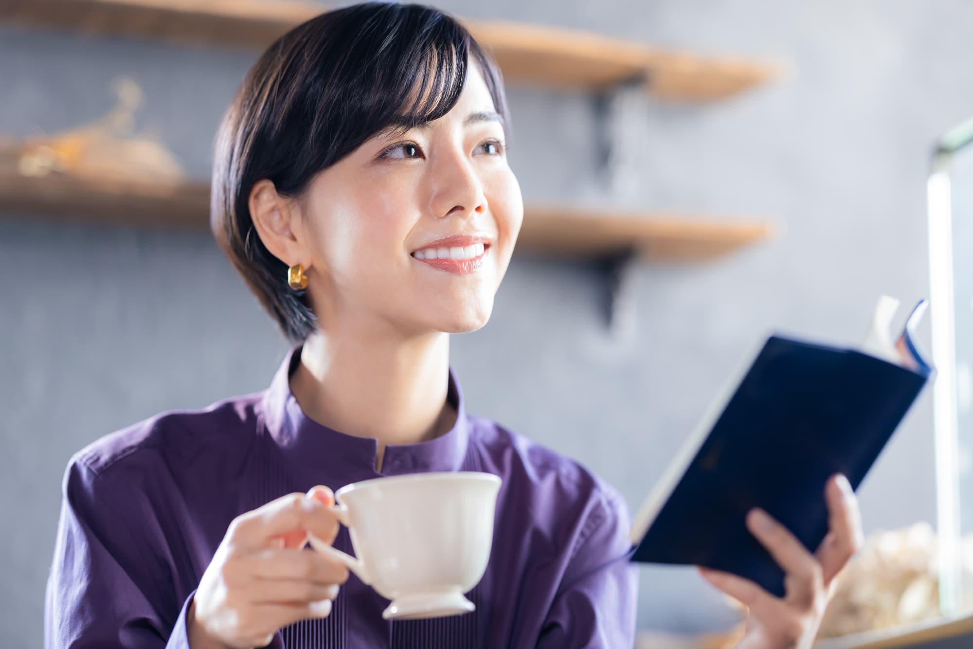 飲み物を飲みながら読書をする笑顔の女性