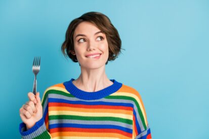 フォーク片手に何を食べても良いのか考えている女性